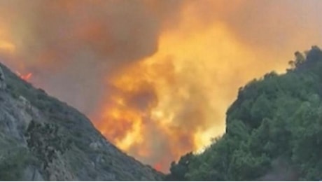 L'incendio a Los Angeles visto dalla strada; le fiamme avvolgono le case e le colline